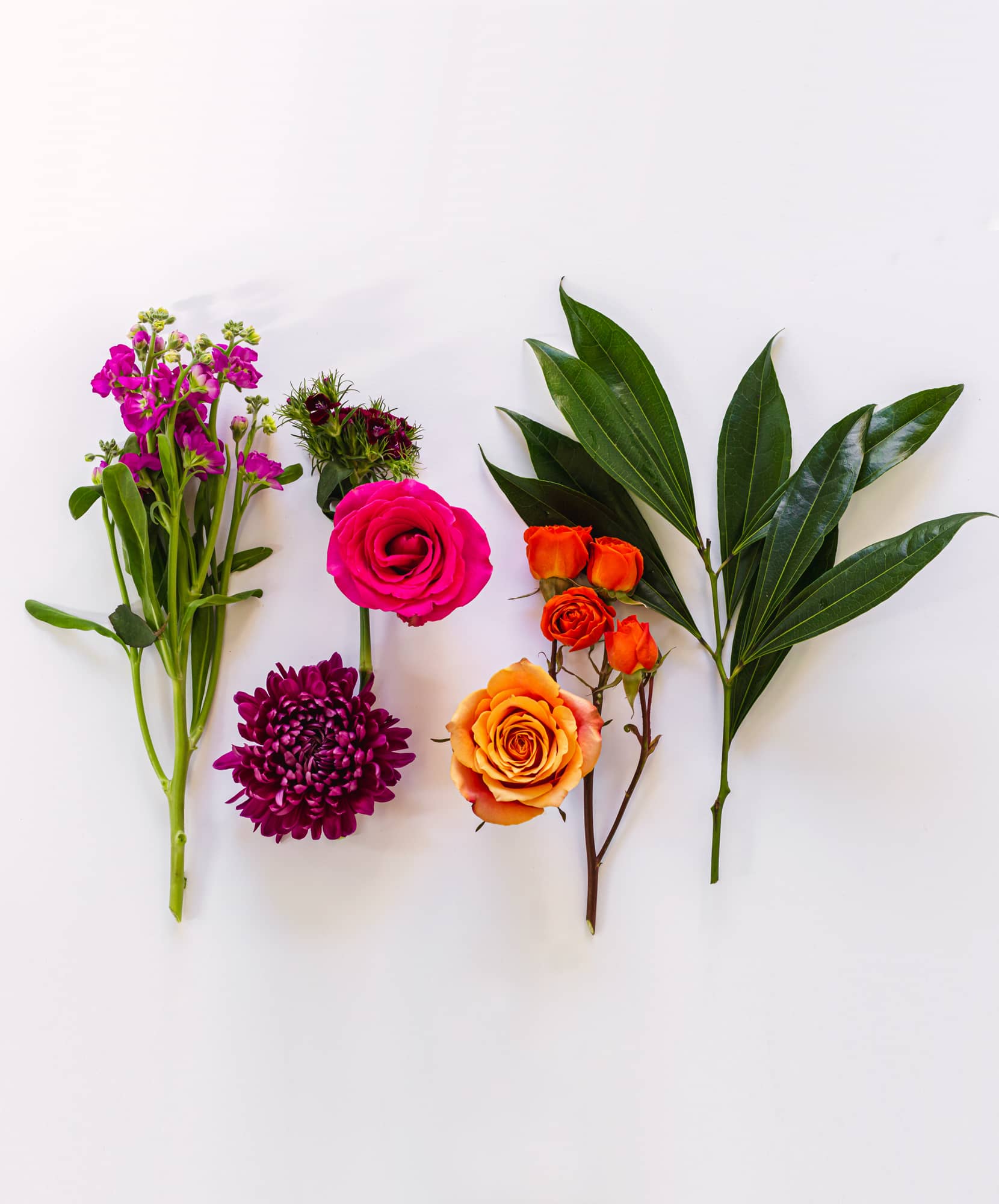 Vibrant floral arrangement featuring pink roses, orange blooms, and lush green leaves.