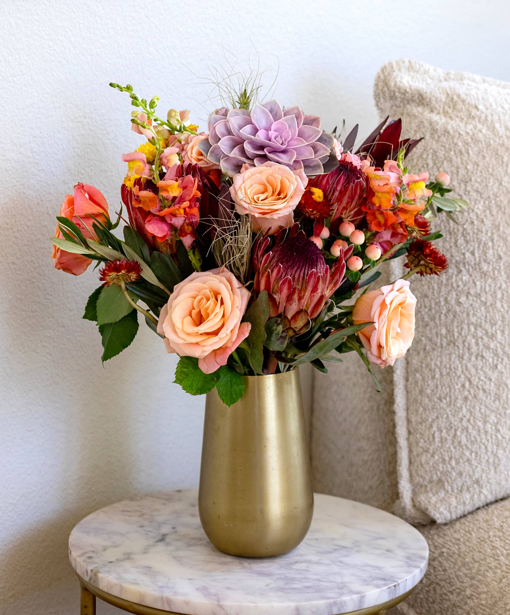 Vibrant floral arrangement featuring blush roses, succulents, and mixed greenery in a vase.